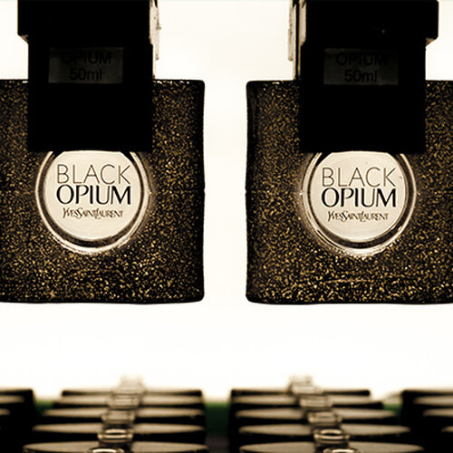 Two bottles of YSL Black Opium perfume hanging upside down.