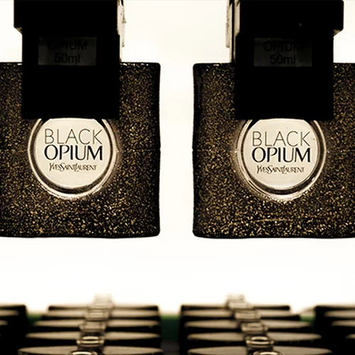 Two bottles of YSL Black Opium perfume hanging upside down.