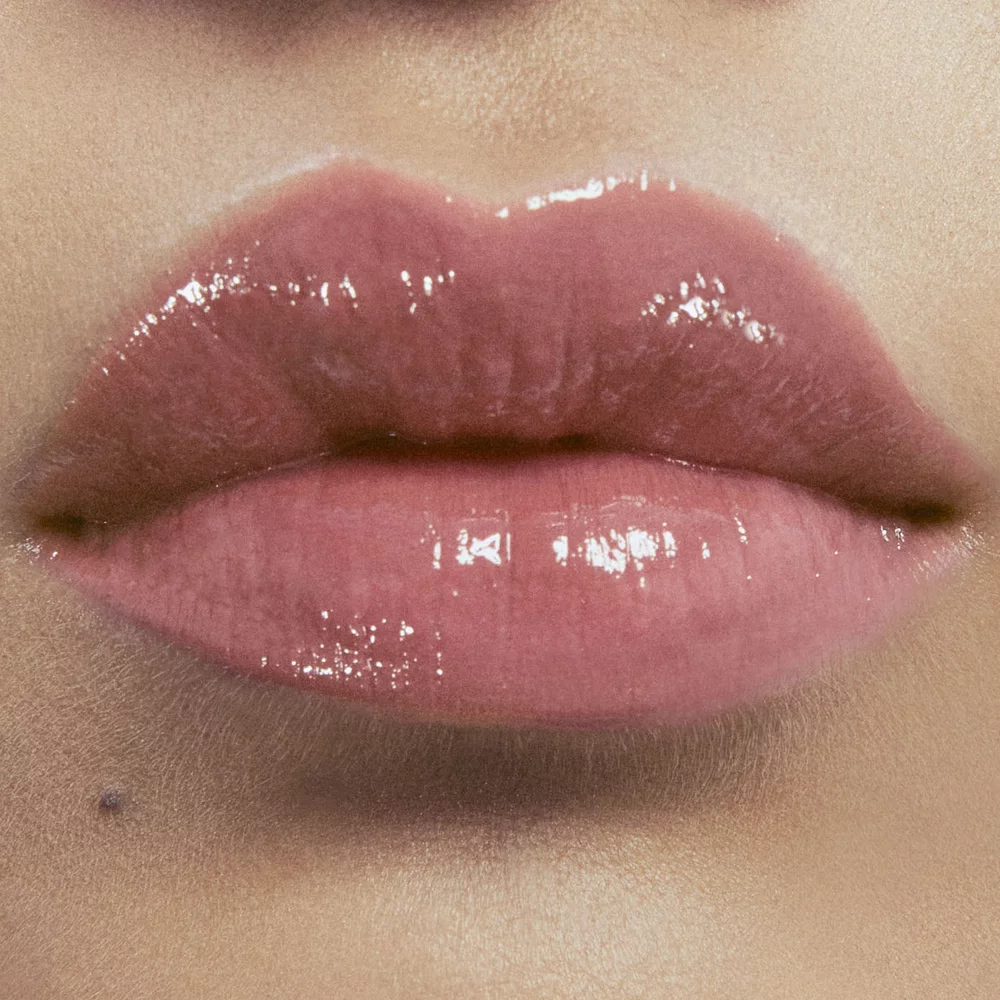 Close-up of lips with glossy nude lipstick.