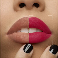 Close-up of lips with one side in nude lipstick and the other in bright pink lipstick, with black nail polish on the fingers.