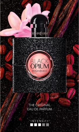 A bottle of Yves Saint Laurent Black Opium perfume with a black glittery finish, surrounded by coffee beans and pink flowers.
