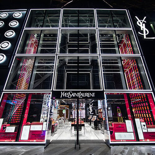 Exterior view of a YSL store with illuminated signage and glass facade.