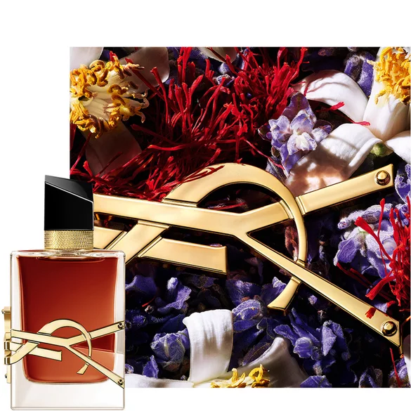 A YSL perfume bottle with flowers in the background.