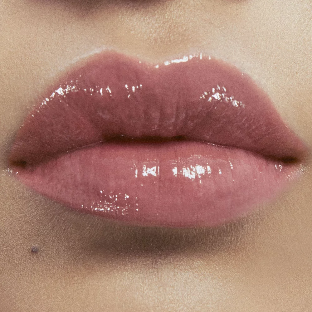 Close-up of lips with glossy nude lipstick.