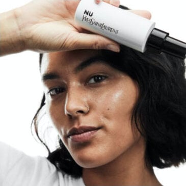 A person holding a tube of YSL Nu product near their face.