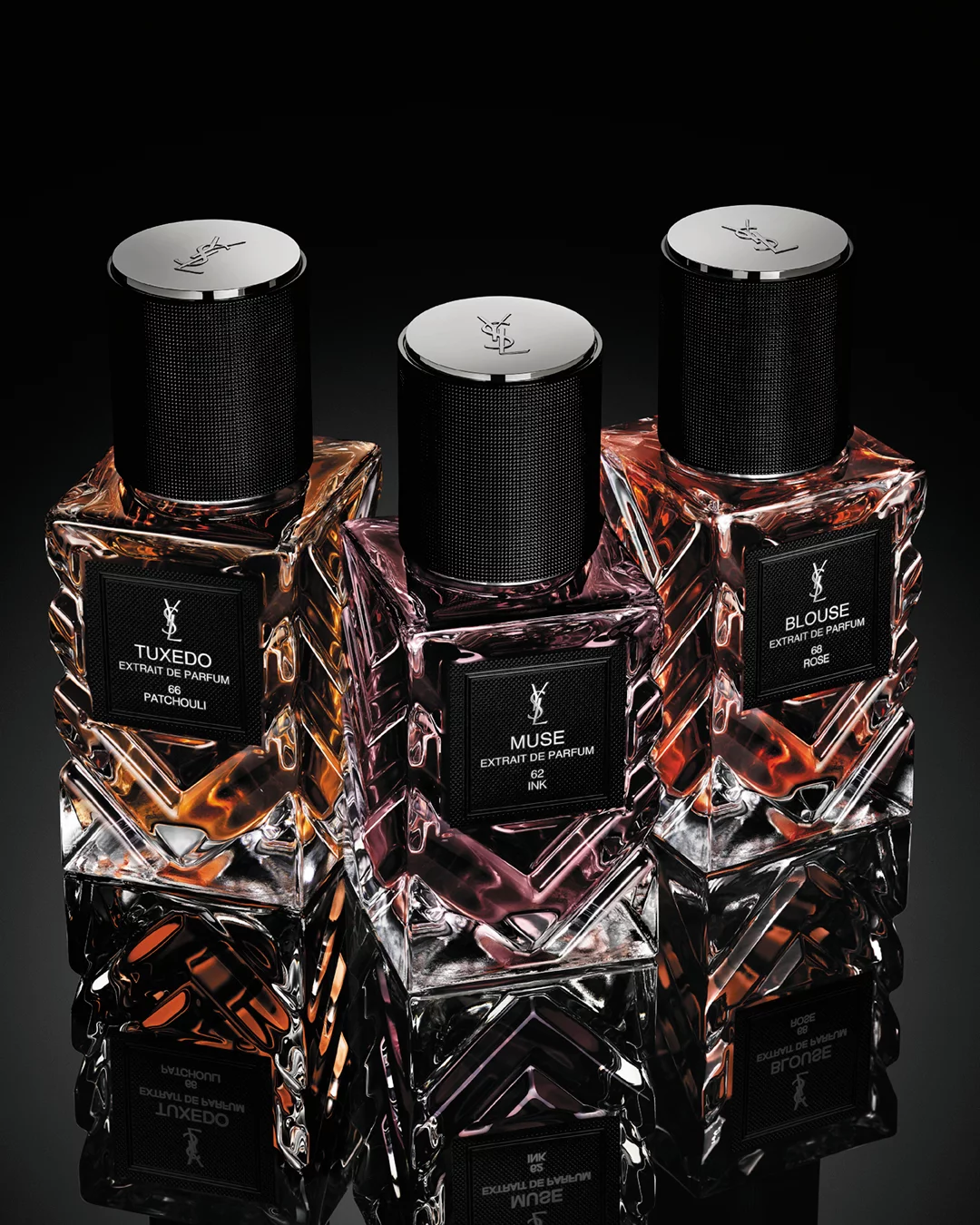 YSL Le Vestiaire des Parfums Tuxedo and Blouse Extrait de Parfum, faceted bottles with black caps, on a reflective black surface.