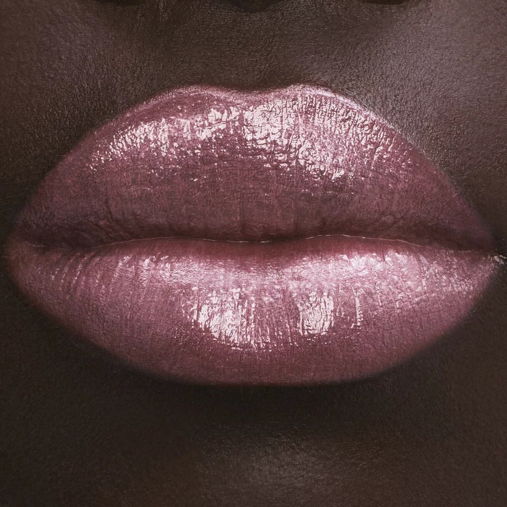 Close-up of lips with glossy pink lipstick on dark skin.