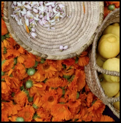 Baskets of flowers and lemons on a bed of orange flowers.