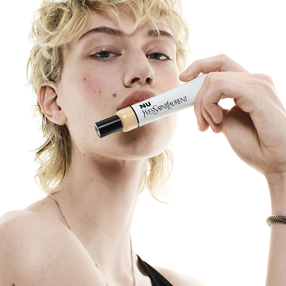 Person holding a YSL product near their face.