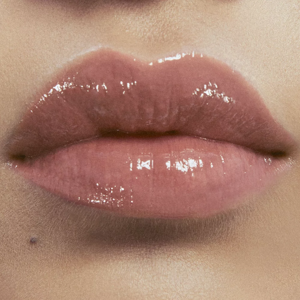 Close-up of lips with glossy nude lipstick.