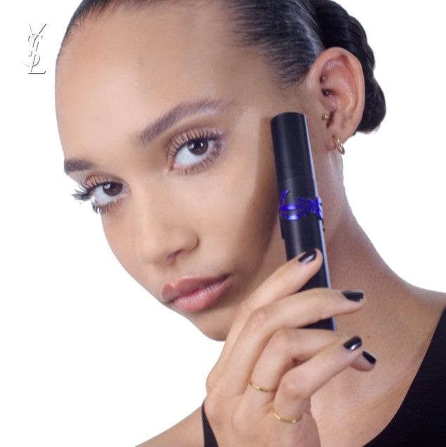 A person holds a YSL product near their face