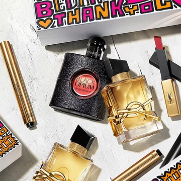 A collection of YSL beauty products including Black Opium and other perfumes, lipstick, and a thank you card.