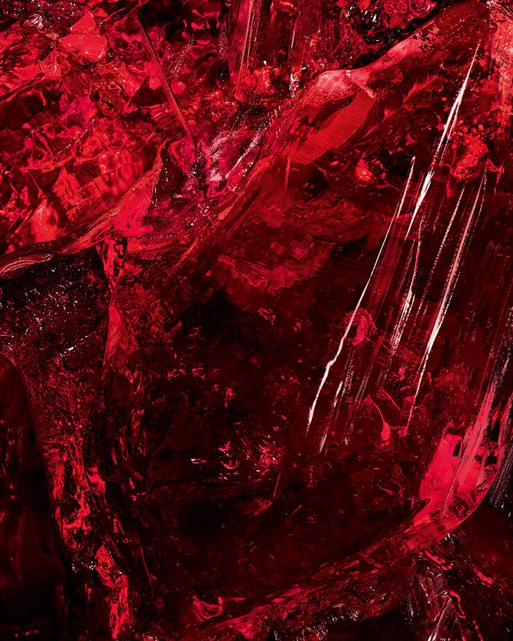 Macro shot of textured red amber
crystal, a key ingredient of CŒUR Eau
de Parfum by YSL, showing its raw
depth.